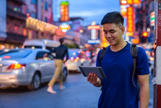 Portret młodego przystojnego turysty azjatyckiego zwiedzania w Chinatown w Bangkoku w Tajlandii