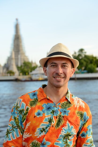 Portret młodego przystojnego turysty na molo z widokiem na rzekę w Bangkoku