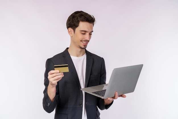 Portret Młodego Przystojnego Uśmiechniętego Biznesmena Trzymającego Kartę Kredytową I Laptopa W Rękach Pisania I Przeglądania Stron Internetowych Na Białym Tle