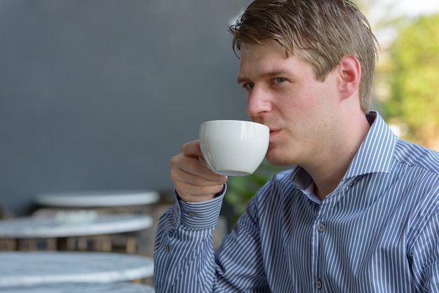Zdjęcie portret młodego przystojny biznesmen blond relaks w kawiarni na świeżym powietrzu