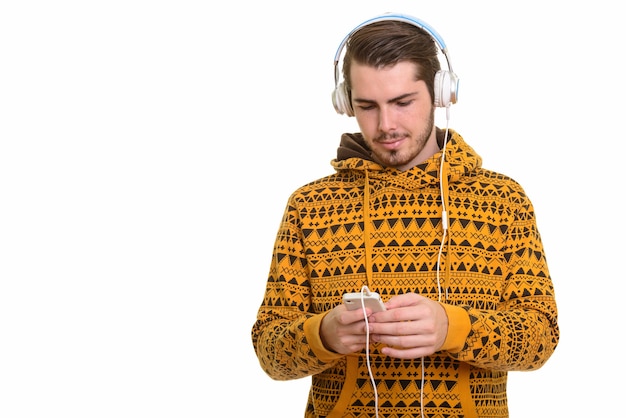 Portret młodego przystojny brodaty mężczyzna słuchanie muzyki podczas korzystania z telefonu