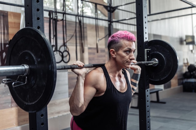 Portret młodego sportowca muskularna kobieta ze sztangą na ramionach w nowoczesnej siłowni krzyżowej. Sport, koncepcja fitness