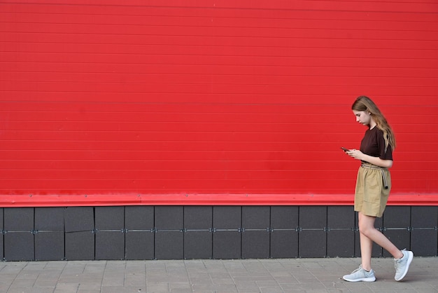 Portret młodego studenta czytającego wiadomość na telefonie komórkowym stylowa ładna dziewczyna rozmawiająca przez telefon komórkowy podczas chodzenia ulicą zaburzenia społeczne zaburzenia technologiczne uzależnione od chorób