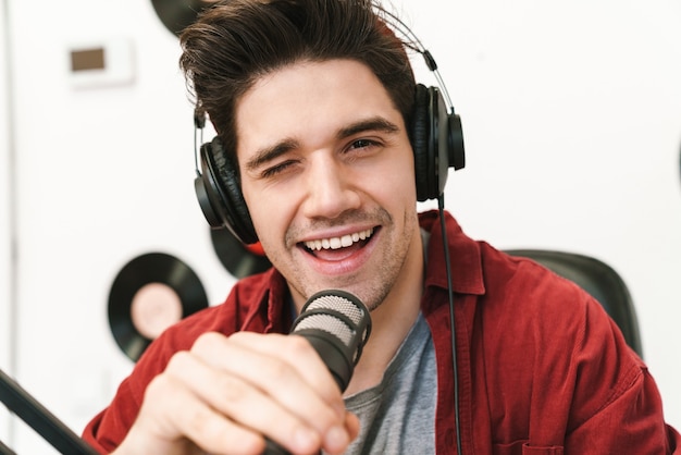 Portret młodego szczęśliwego kaukaskiego mężczyzny występującego w programie radiowym podczas nagrywania podcastu do programu online