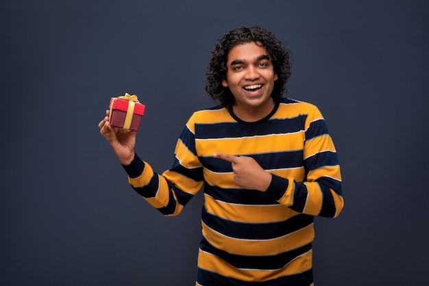 Portret młodego szczęśliwego uśmiechniętego przystojnego mężczyzny trzymającego pudełko na szarym tle