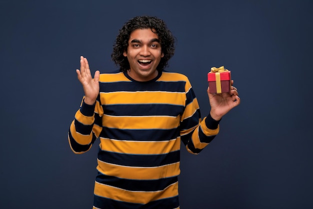 Portret młodego szczęśliwego uśmiechniętego przystojnego mężczyzny trzymającego pudełko na szarym tle