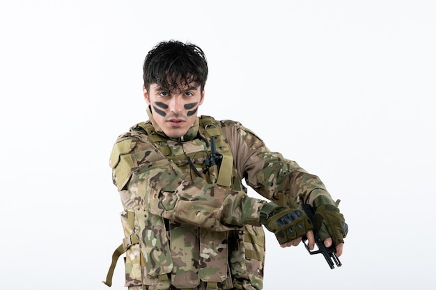 Portret młodego żołnierza w kamuflażu na białej ścianie