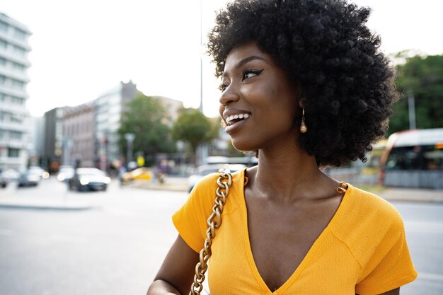 Portret młodej afroamerykanki uśmiechniętej stojącej w mieście