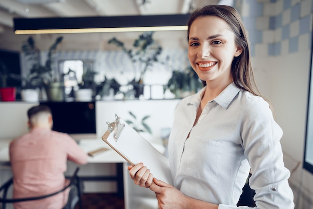 Portret Młodej Atrakcyjnej Bizneswoman Trzymającej Schowek W Biurze