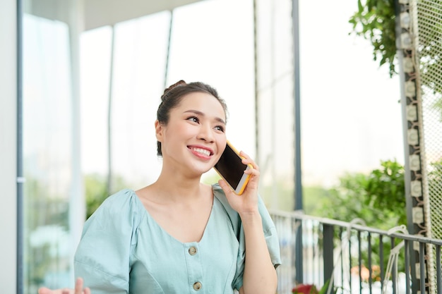 Portret młodej azjatyckiej kobiety trzymającej telefon na balkonie