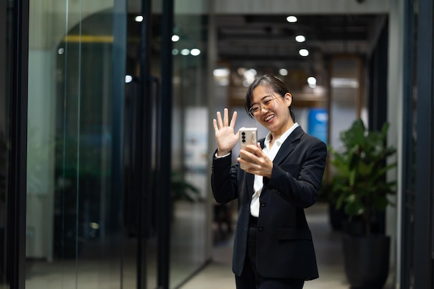 Zdjęcie portret młodej azjatyckiej kobiety z uśmiechem szczęśliwa azjatycka bizneswoman używająca telefonu komórkowego nowoczesne biuro miejsce pracy