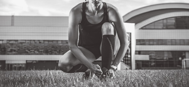 Portret młodej biegaczki, która sznuruje buty na stadionie piłkarskim. Koncepcja sportu.