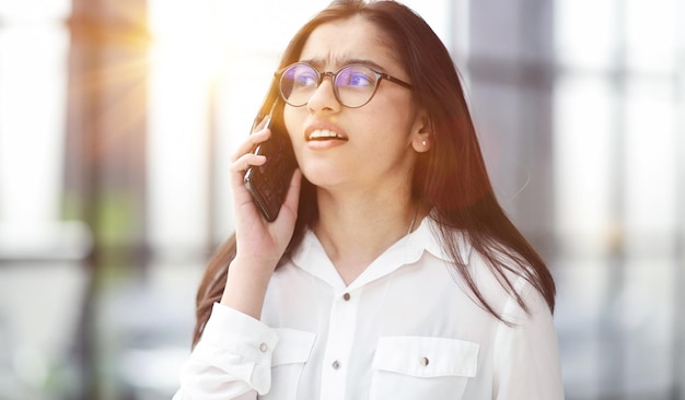 Portret młodej biznesowej kobiety rozmawiającej przez telefon komórkowy w okularach ofand
