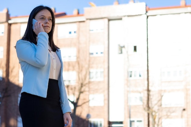 Portret młodej bizneswoman kaukaskiej rozmawiającej przez telefon na ulicy