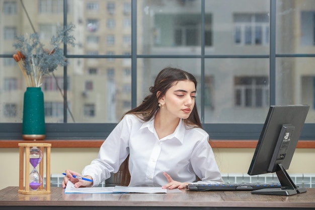 Portret młodej bizneswoman siedzącej przy biurku i patrzącej na swój komputer Wysokiej jakości zdjęcie