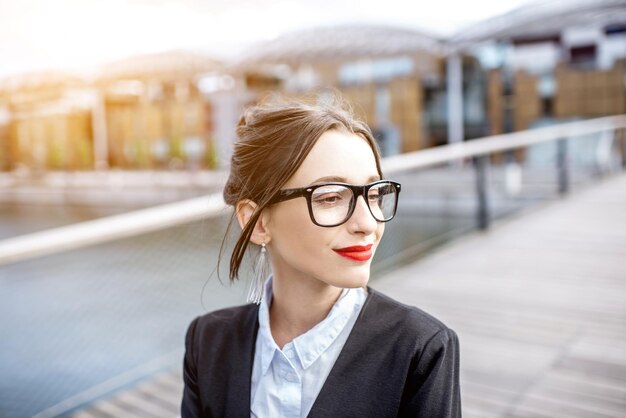 Portret młodej bizneswoman stojącej na moście w nowoczesnej dzielnicy mieszkalnej w Lyonie