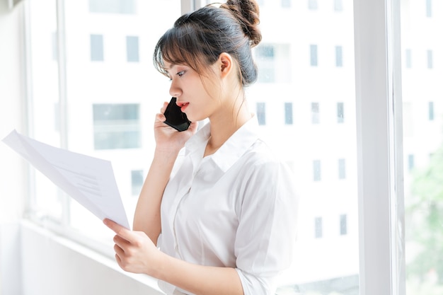 Portret Młodej Bizneswoman Stojącej Przy Oknie I Wykonującej Rozmowy Telefoniczne Ze Swoim Partnerem