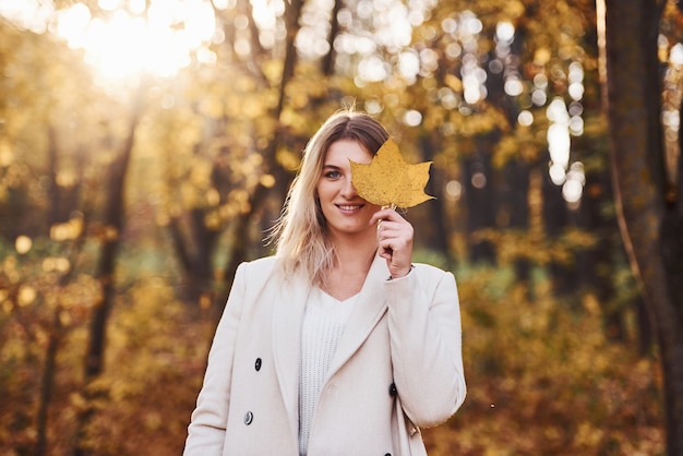 Portret młodej brunetki z liściem, który jest w lesie jesienią w ciągu dnia.