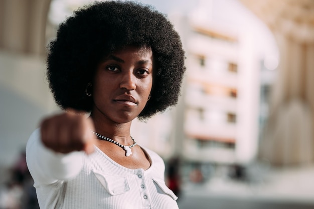Portret młodej czarnej kobiety z afro włosami, gestykulującej z zaciśniętą pięścią, symbolizującej siłę Koncepcja mocy dziewczyny Pozioma