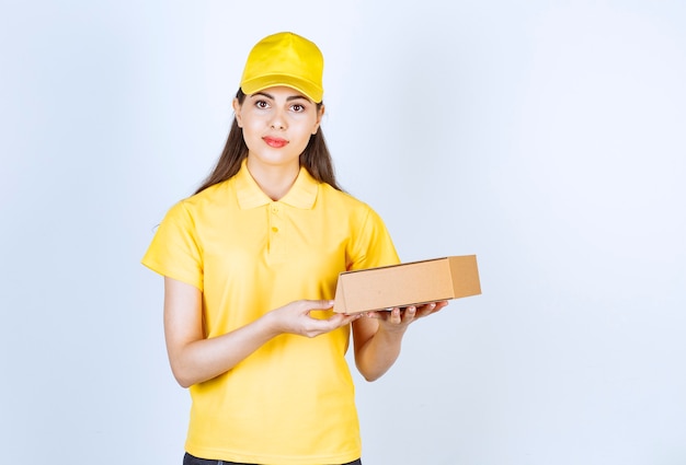 Portret młodej deliverywoman trzyma pojedyncze pudełko na bielu.