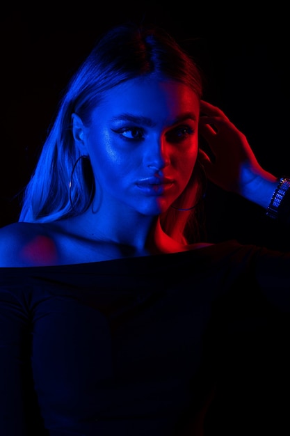 Portret młodej dziewczyny moda w czerwonym i niebieskim świetle neonowym w studio.