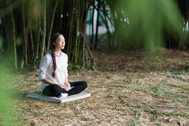 Portret młodej dziewczyny robi medytację i jogę w bambusowym lesie