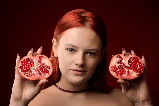 Portret młodej dziewczyny z Rude włosy i owoce granatu w ręce