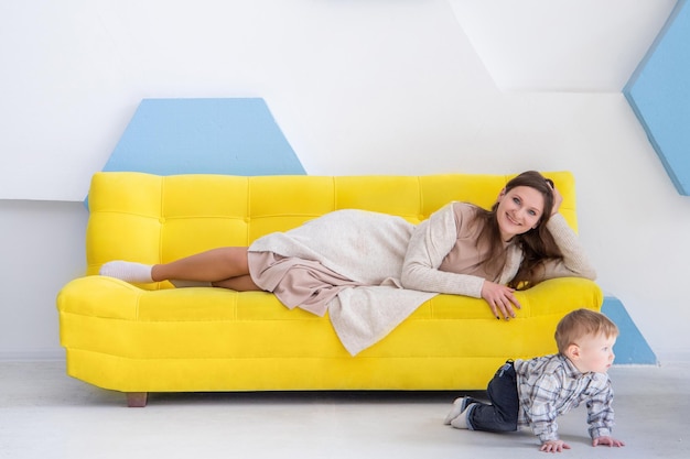 Portret młodej europejki z małym dzieckiem na kanapie w jasnym, pozytywnym wnętrzu