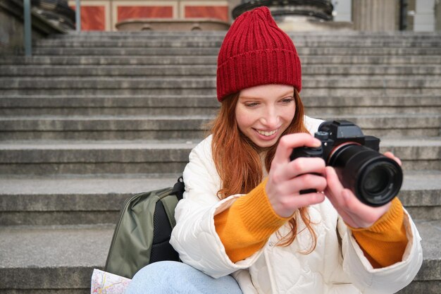 Portret młodej fotografki siedzi na schodach z profesjonalnym aparatem robi zdjęcia na zewnątrz ma