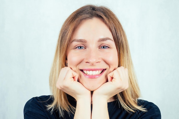 Zdjęcie portret młodej i pięknej blond kobiety uśmiechniętej szerokim uśmiechem w czarnej koszulce.