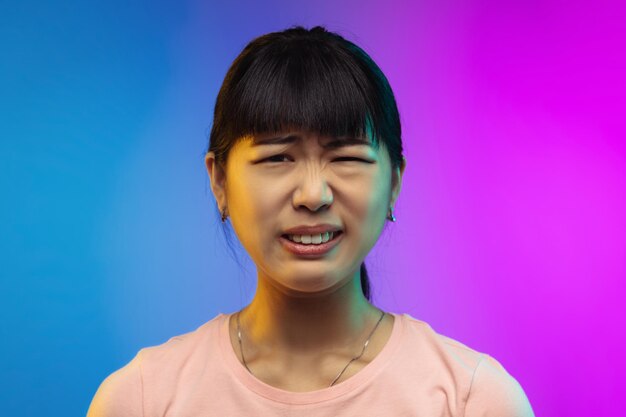 Portret młodej kobiety azjatyckiej na gradientowym studio w neonowym kolorze