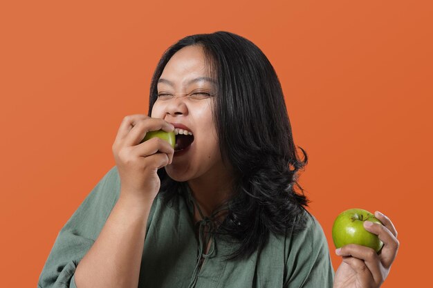 Portret młodej kobiety Azji, prowadzi zdrowy tryb życia. trzyma i gryzie świeże zielone jabłko