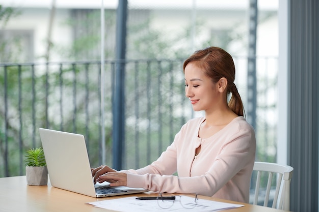 Portret młodej kobiety biznesu korzystającej z laptopa w biurze