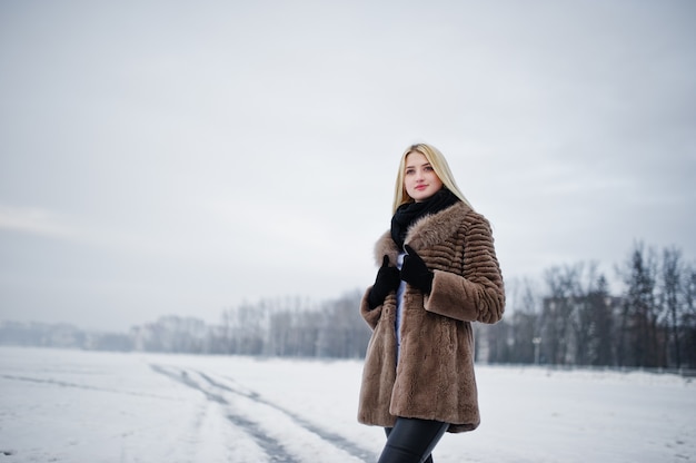 Portret młodej kobiety blondynka elegancji w futrze, mglista rzeka na lodzie zimowym.