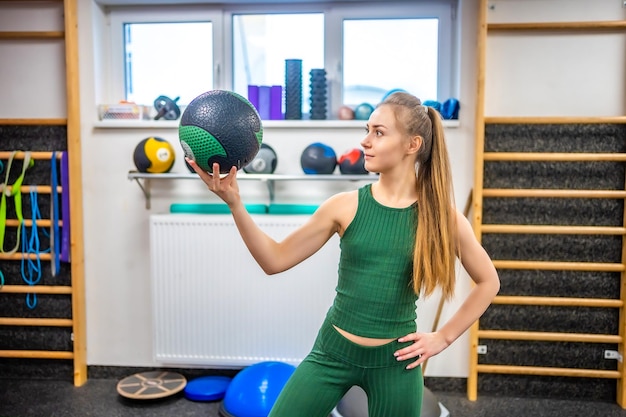 Portret młodej kobiety instruktora fitness z piłką w dłoni