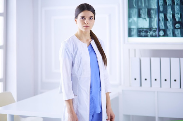 Portret młodej kobiety lekarza w białym fartuchu stojącej w szpitalu