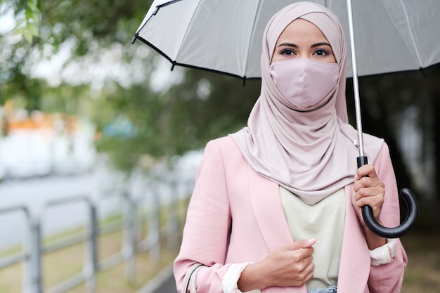 Portret Młodej Kobiety Muzułmańskiej Z Zakrytymi Ustami Trzymając Parasol Podczas Chodzenia W Deszczu