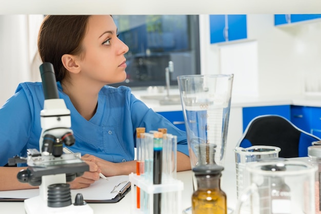 Zdjęcie portret młodej kobiety naukowca w mundurze pracującej nad niektórymi badaniami w laboratorium. koncepcja opieki zdrowotnej i biotechnologii