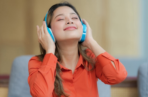 Portret młodej kobiety piękne słuchanie muzyki z uśmiechniętą twarz siedzi w pobliżu okna w kreatywnym biurze lub kawiarni