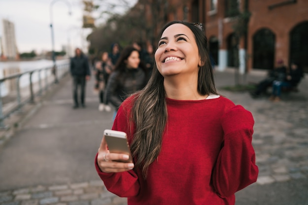 Portret młodej kobiety piękne trzymając telefon komórkowy z pomyślnym wyrazem twarzy, świętując coś.