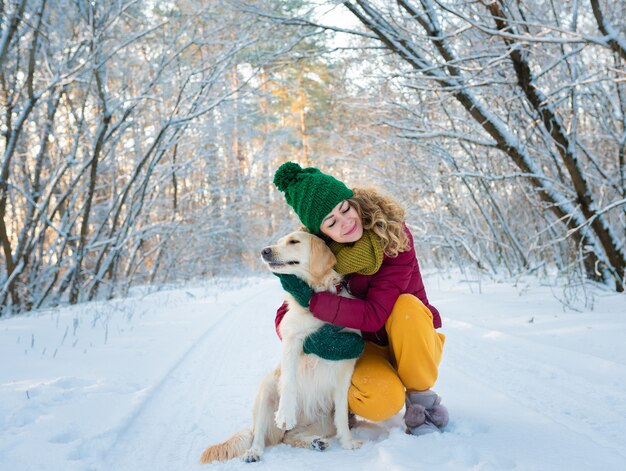 Portret młodej kobiety przytulanie białego golden retriever psa w zimie