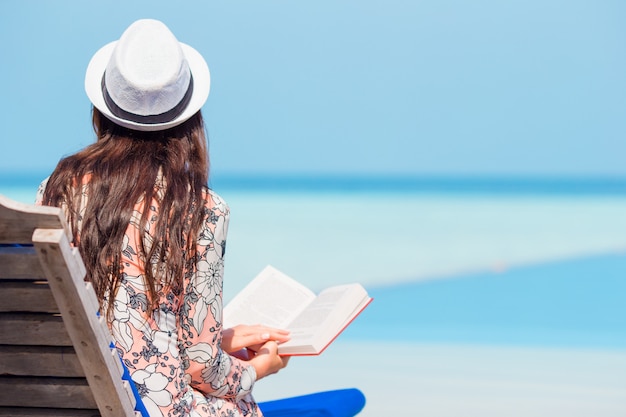 Portret młodej kobiety relaks na plaży, czytając książkę