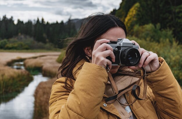 Portret młodej kobiety robiącej zdjęcia pięknej jesieni przyrody za pomocą starego filmu