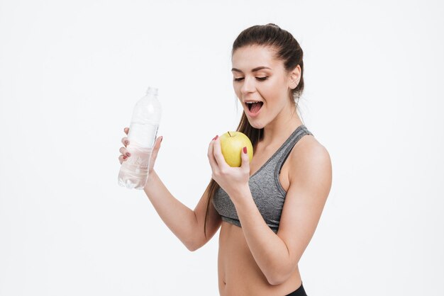 Portret Młodej Kobiety Sportowej Trzymającej Butelkę Wody I Gryzące Jabłko Na Białym Tle