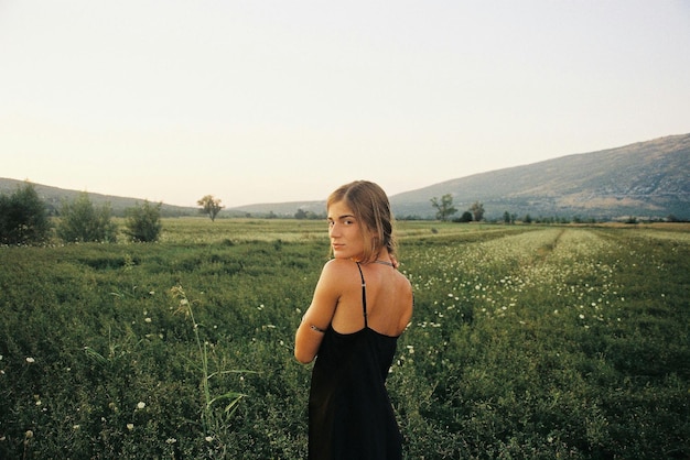 Portret młodej kobiety stojącej na polu na czystym niebie