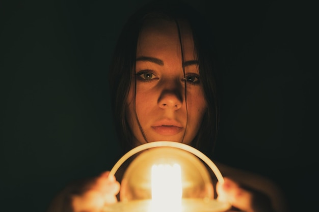 Zdjęcie portret młodej kobiety trzymającej oświetlony sprzęt oświetleniowy na czarnym tle
