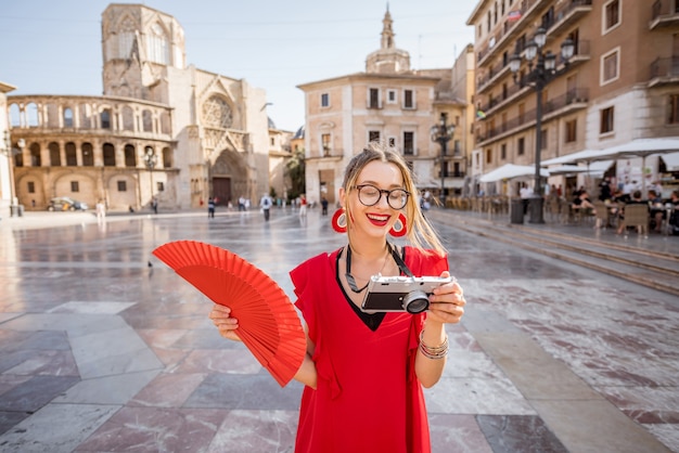 Portret Młodej Kobiety Turysty W Czerwonej Sukience Z Wentylatorem Na Centralnym Placu Starego Miasta W Walencji, Hiszpania