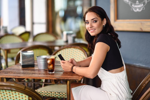 Portret młodej kobiety uśmiechającej się podczas picia na stole w restauracji
