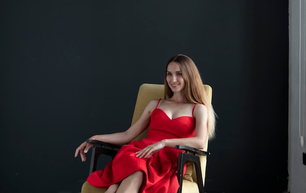 portret młodej kobiety w czerwonej sukience siedzącej na krześle