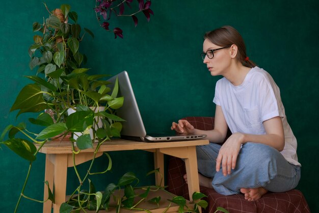 Portret młodej kobiety w okularach korzystającej z laptopa siedząc w sypialni